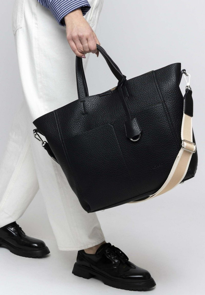 Black leather tote bag with a textured finish, featuring dual top handles and a long adjustable strap in contrasting tan.