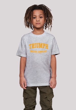 Gray cotton T-shirt with "TRIUMPH MOTOR COMPANY" in bold yellow lettering, paired with olive green cargo pants. Short sleeves and relaxed fit.