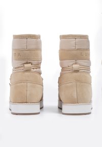 Bottines beiges en cuir suédé et matériaux synthétiques, dotées d'un design rembourré, d'une finition texturée et d'une semelle en caoutchouc blanc.