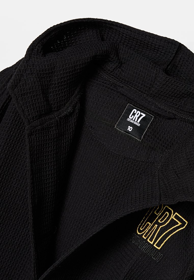 Czarna, fakturowana bluza z kapturem z wzorem w waffle, z żółtym haftowanym logo i metką rozmiaru na wewnętrznej etykiecie.
