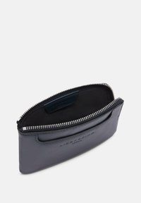 Portefeuille en cuir gris avec fermeture éclair, présentant une texture lisse et une doublure en suède à l'intérieur. Inclut un logo embossé et un compartiment pour cartes.