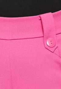 Roza elegantna hlače z gladko teksturo, ki imajo enojno gumbno zapiranje in čiste šive okoli pasu.