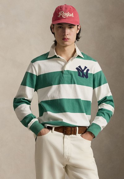 Rohelise ja valge triibuline ragbipluus mereväe sinise NY logoga, koos roosa nokamütsi, millel on kiri "Ralph", pruuni vöö ja valgete pükstega.