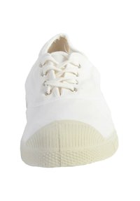 Zapatilla de lona blanca con punta redonda, cordones planos y ojales plateados. Suela de goma con patrón texturizado, que presenta un talón redondeado y punta texturizada.