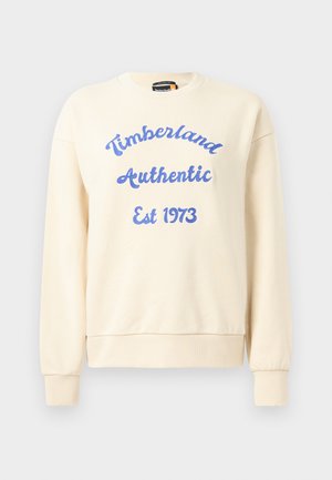 Kremgenser med blå "Timberland Authentic Est 1973" tekst. Har rund hals og ribbede mansjetter. Myk stofftekstur, uformell design.