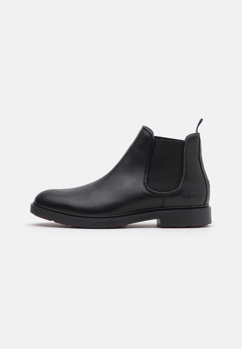 Bottine Chelsea en cuir noir à la cheville avec panneau latéral élastique, languette au talon et semelle basse, présentée sur un fond clair uni.