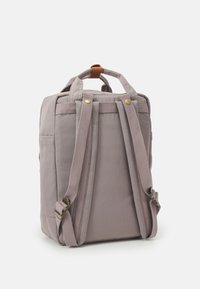 Gray fabric backpack with padded sides, dual top handles, adjustable straps, and brass hardware accents. Minimalist design with side pocket.
