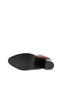 Sole di scarpe in pelle marrone con punta affusolata, caratterizzata da un tacco in gomma nera e una superficie texturizzata per aderire meglio. Design semplice con dettagli minimi.