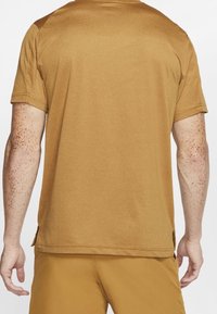 Braunes T-Shirt mit kurzen Ärmeln, glatter Textur, seitlichen Schlitzen am Saum und entspannter Passform, von hinten gezeigt.