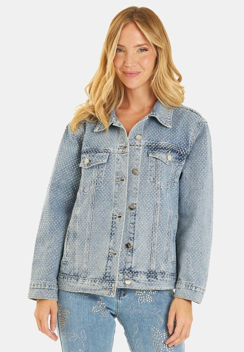 Veste en denim bleu clair avec des détails de clous décoratifs. Comprend deux poches poitrine, du matériel en argent et un design de col classique.