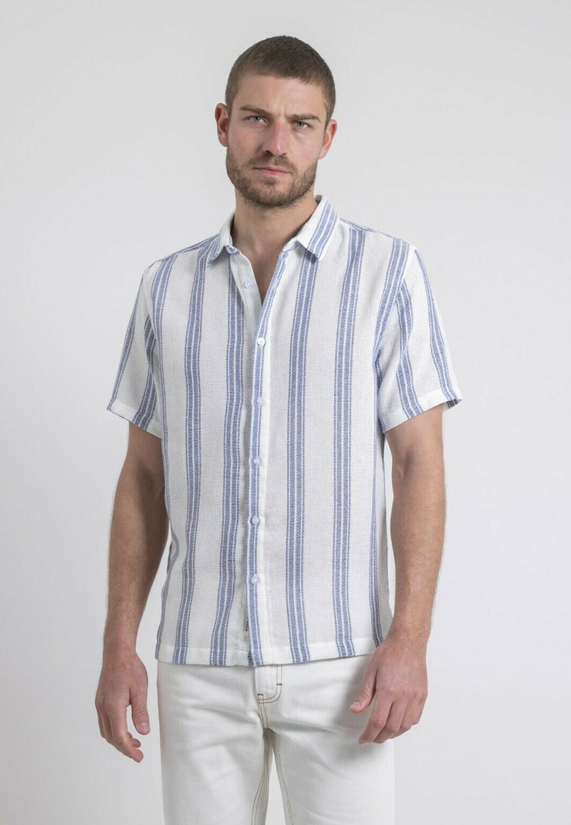 Chemise à manches courtes à boutons en blanc avec des rayures verticales bleues. Fabriquée en tissu texturé avec un col et un ourlet droit.