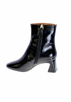 Stivale alla caviglia in pelle nera con punta affusolata, cerniera laterale e tacco a blocco medio. La superficie ha una finitura lucida e cuciture minime.