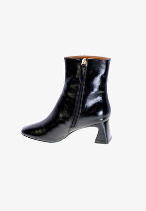 Stivale alla caviglia in pelle nera con punta affusolata, cerniera laterale e tacco a blocco medio. La superficie ha una finitura lucida e cuciture minime.