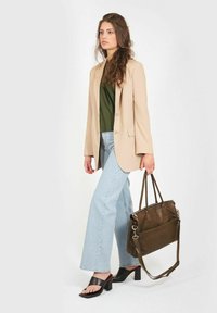 Beige blazer, grøn top, lyseblå brede jeans, sorte hæle sandaler og en mørkebrun læder tote bag med dobbelte stropper og frontlommer.