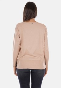 Maglione beige con vestibilità rilassata e orlo a coste, caratterizzato da un collo rotondo e maniche lunghe, realizzato in morbido tessuto lavorato a maglia.