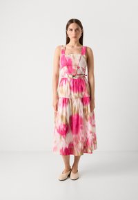 Robe midi florale avec des teintes rose et crème, présentant un décolleté carré, des bretelles épaisses et une taille ceinturée. Tissu léger, silhouette fluide.