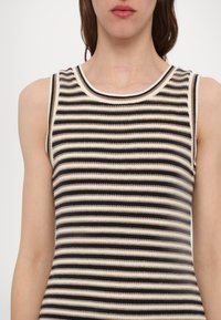 Top a strisce con scollo ampio, caratterizzato da strisce orizzontali in nero, beige e crema. La trama a coste conferisce dimensione al tessuto.