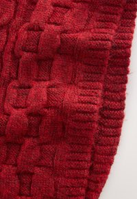 Écharpe rouge tricotée avec un motif texturé en tissu tissé, comprenant des carrés en relief et des bords côtelés, fabriquée à partir d'un fil doux et épais.