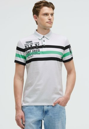 Polo-Shirt aus heller grauer Baumwolle mit schwarzen und grünen Streifen; verfügt über drei Knöpfe am Kragen und bedruckte Textdetails. Kurzarm.