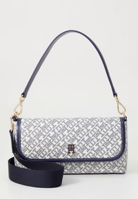 Kabelka v námořnicky modré a bílé s geometrickým vzorem, obdélníkového tvaru, vyrobená z texturované látky, se zlatými kovovými prvky a odnímatelným popruhem pro více možností nošení.