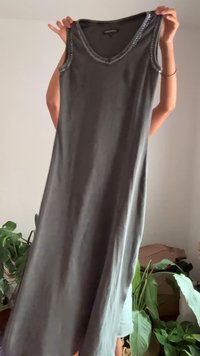 Rochie gri fără mâneci cu decolteu în V, decorată cu mărgeluțe de-a lungul decolteului. Țesătură ușoară și fluidă.
