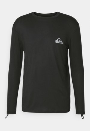 Čierne tričko s dlhým rukávom vyrobené z ľahkej látky. Obsahuje malé šedé logo na hrudi a manžety s nastaviteľnými slučkami.