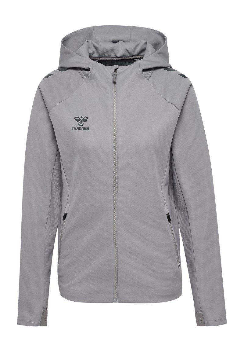 Giacca grigia con zip e cappuccio, caratterizzata da una texture liscia, due tasche laterali e accenti neri sulle spalle e sul cappuccio. Logo Hummel sul petto.