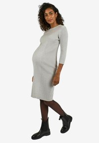 Rochie midi gri cu dungi, cu mâneci trei sferturi, siluetă ajustată, purtată cu botine negre și pe deasupra colanți negri.