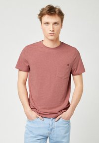 Heren t-shirt met korte mouwen in een stofroze kleur, gemaakt van zachte stof, met een borstzak en een klein logootje boven de zak.