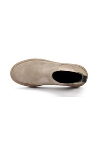 Zapato slip-on de ante beige con punta redonda, panel lateral elástico y suela de goma plana. Interior forrado con tejido suave para mayor comodidad.