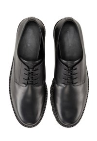 Scarpe nere in pelle con tomaia liscia, design con lacci e punta rotonda. Suola in gomma testurizzata con cuciture lungo il bordo.