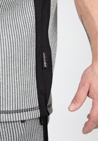 Grijs en zwarte gestreepte sportkleding met een mesh-paneel en merkimprint, met een comfortabele textuur en een gebogen zoomdetail.