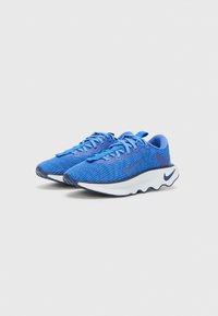 Blue athletic shoes with a textured upper, contrast laces, and a white cushioned sole featuring a wavy design and a logo on the side.