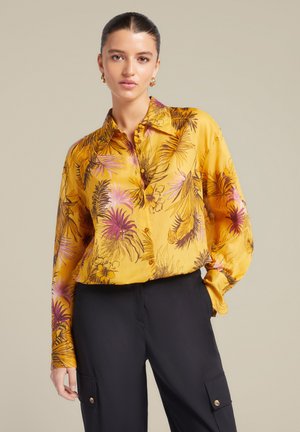 Geel zijden blouse met een bloemenpatroon in roze en paarse tinten, met een knoopsluiting aan de voorkant, lange mouwen en een ontspannen pasvorm.