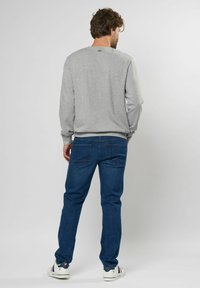 Grijze katoen sweatshirt met lange mouwen, ronde halslijn en geribbelde manchetten, gecombineerd met blauwe denim jeans en witte sneakers.