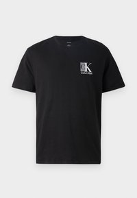 Black cotton t-shirt with a crew neckline. Features a front logo in gray featuring "CK" and "Calvin Klein." Short sleeves and relaxed fit.