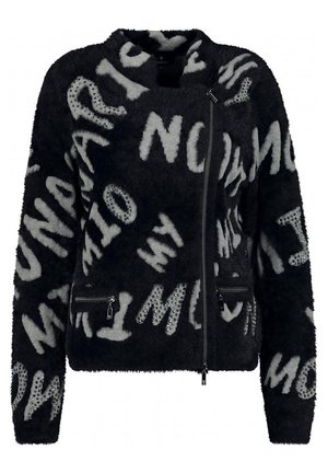 Veste noire en tissu duveteux avec lettres abstraites grises et ornements cloutés, dotée d'une fermeture éclair asymétrique et de poches zippées.