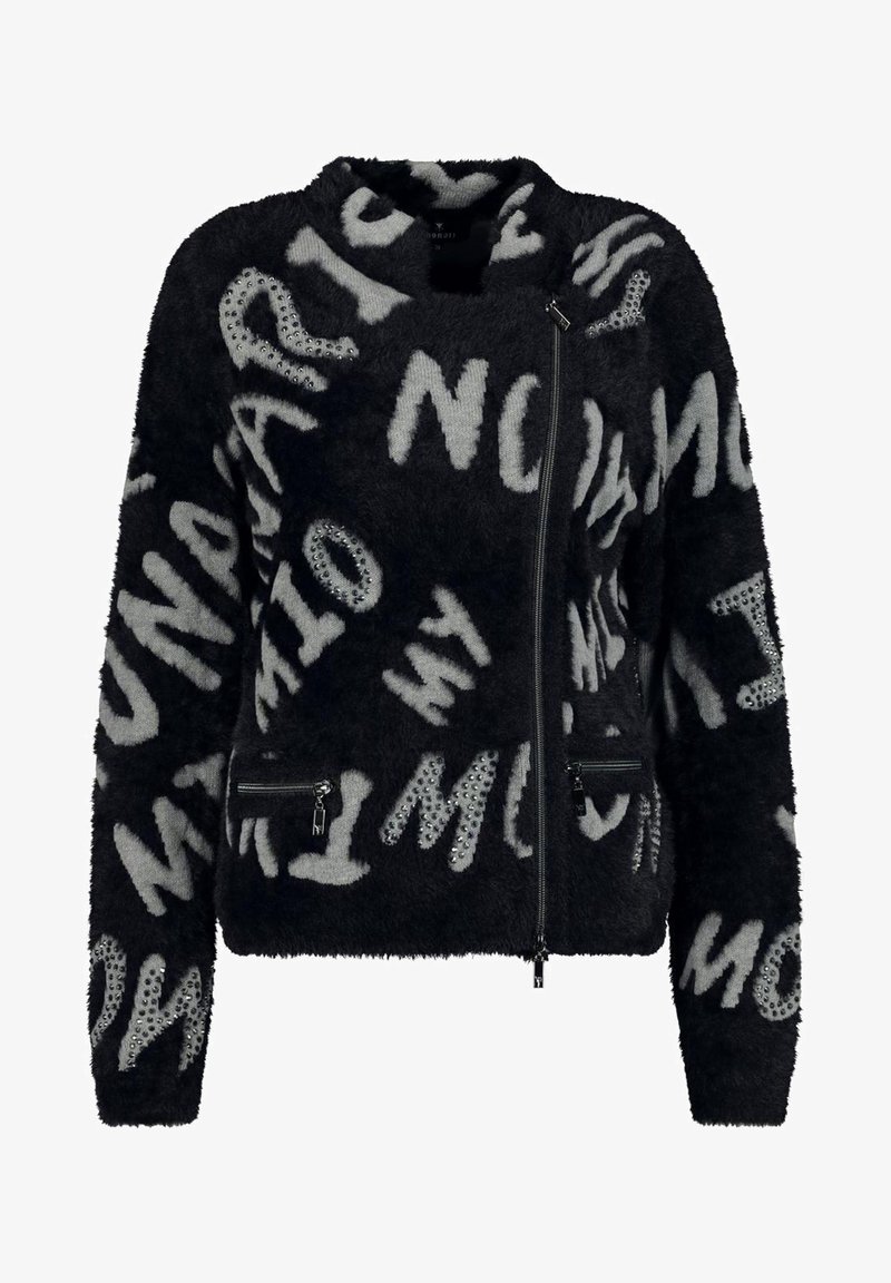 Veste noire en tissu duveteux avec lettres abstraites grises et ornements cloutés, dotée d'une fermeture éclair asymétrique et de poches zippées.