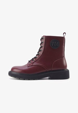 Burgundi odinė kulkšnės boot'as su juodais raišteliais, apvaliu pirštu, storu padu ir apvalia logotipo etikete šone. Yra sidabriniai akių laikikliai.