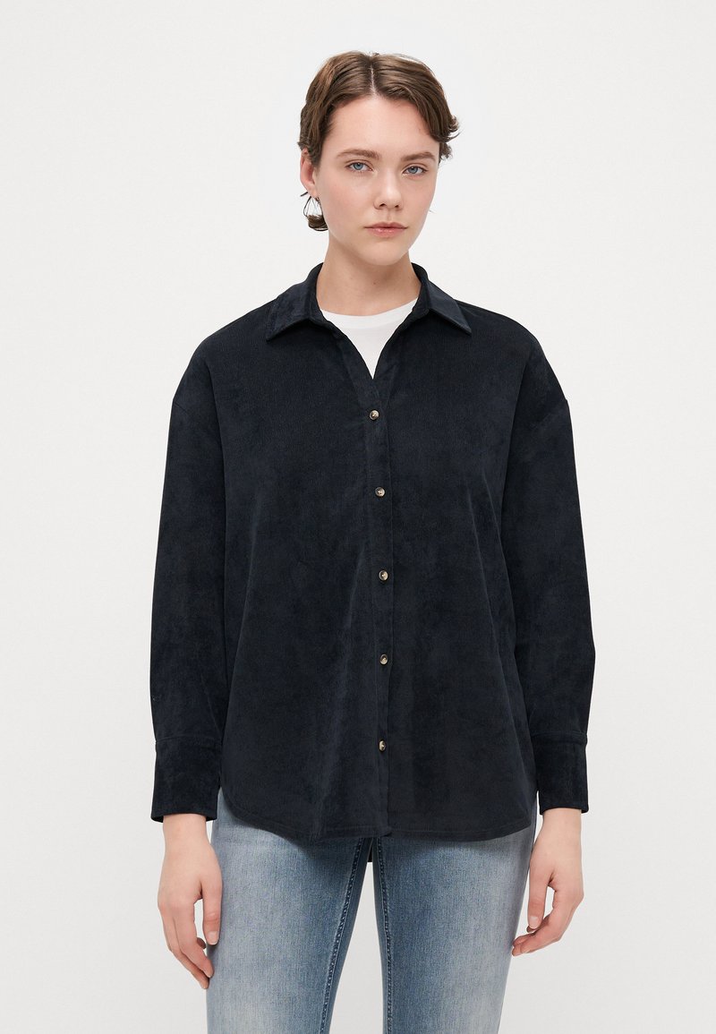 Mørkeblå, myk kordfløyelskjorte med spiss krage, knappestolpe foran og lange ermer, med en avslappet passform og subtil tekstur.