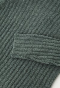 Tessuto di maglione a coste di un verde scuro, con polsini ripiegati, caratterizzato da una morbida texture e un motivo a righe verticali.