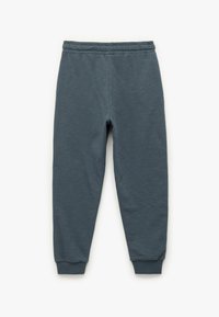 Grå sweatpants lavet af blødt stof, med elastisk talje og afsluttede ankler, der har en glat og let struktureret finish.