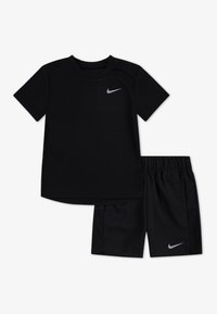 T-shirt preta da Nike com mangas curtas e um logo prateado, emparelhada com calções pretos com painéis laterais em malha e um cós elástico.