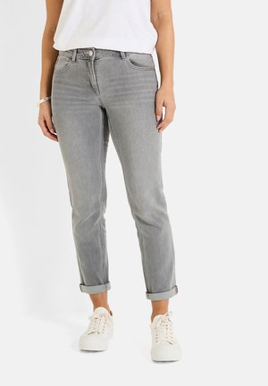 Jeans de mezclilla gris con un diseño ajustado, puños doblados, bolsillos frontales y cierre de botón metálico, combinados con zapatillas blancas.