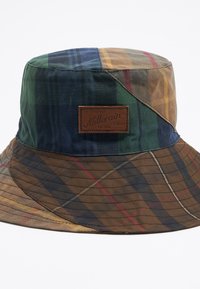 Muts in een meerkleurig ruitpatroon met groen, blauw, bruin en gele tinten. Inclusief een bruin leren logo patch.