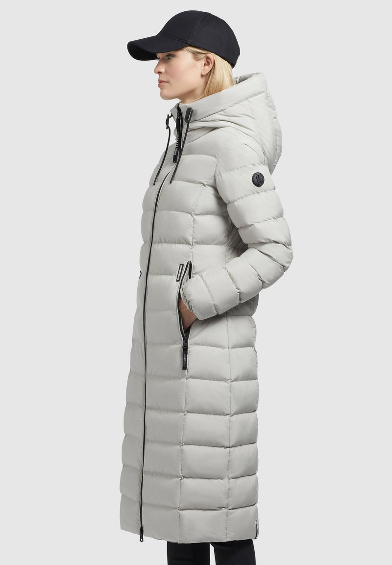 Helle graue Steppjacke mit knielangem Design, horizontalem Steppmuster, schwarzem Reißverschluss und Akzentlogo am Ärmel. Verfügt über eine Kapuze.