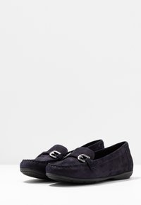 Marineblaue Wildlederloafer mit silbernen Hardware-Details, runder Zehenform und flacher Gummisohle. Mit einer Naht entlang der oberen Kante.