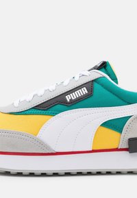 Färgglad sneaker med grå mocka tå, vita och teal paneler, gula detaljer och en svart etikett med "PUMA" i vit text.