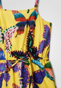 Gelbes Kleid mit einem bunten Schmetterlingsdruck, mit tailliertem Schnitt und verstellbaren Trägern. Das Material wirkt weich und leicht.