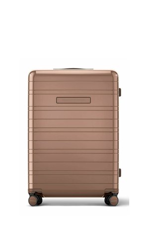 Hard-shell suitcase in metallic bronze with four spinner wheels and a recessed handle on front, shown from the front on a white background.